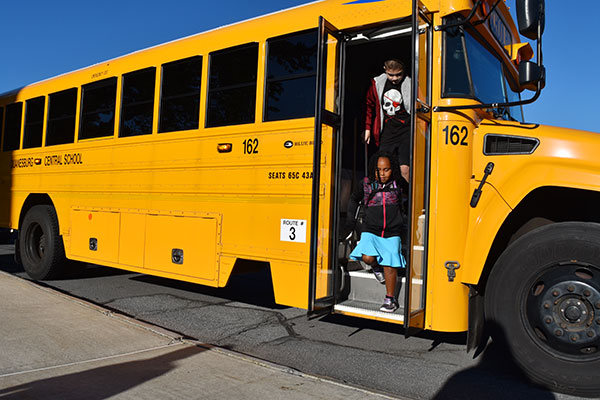 two students getting off a bus 