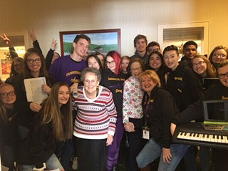 choir poses as a group with nursing home resident