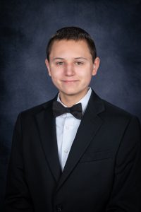 a young man with short dark hair wears a suit and bowtie for a posed photo