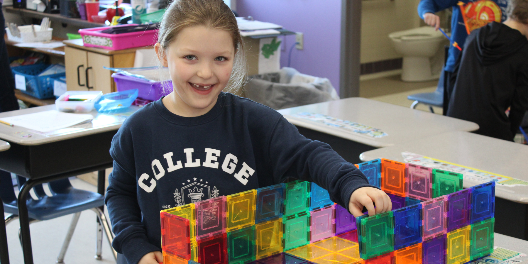 a young student missing her front teeth creates a colorful design 