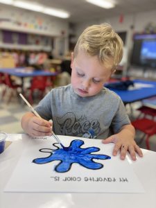 a boy paints a picture blue