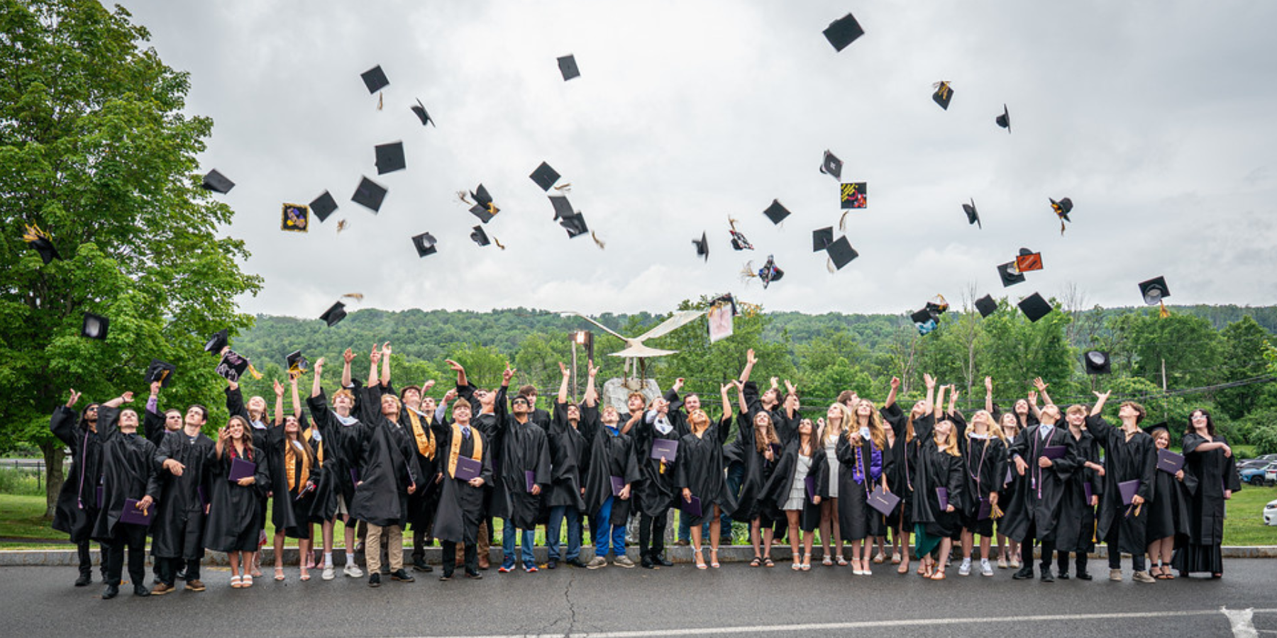 a class of graduates toss their mortar caps into the air to celebrate