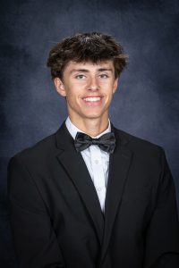a young man with dark hair wears a suit and bowtie for a posed photo