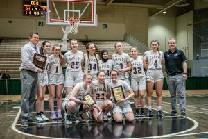 a girls basketball team poses together on a basketball court