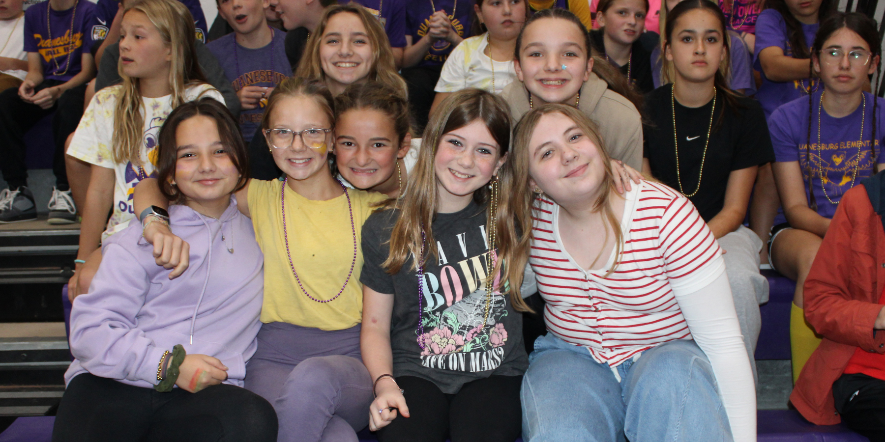 a group of middle school students sit in the bleachers of a gymnasium